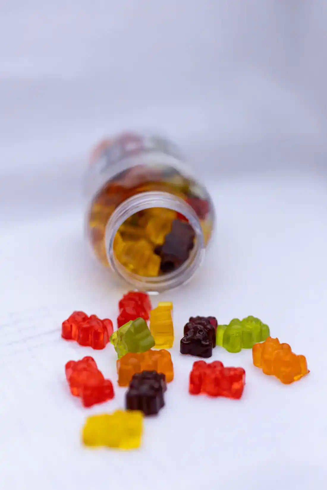 Gummy bear vitamins spilling from a plastic bottle.