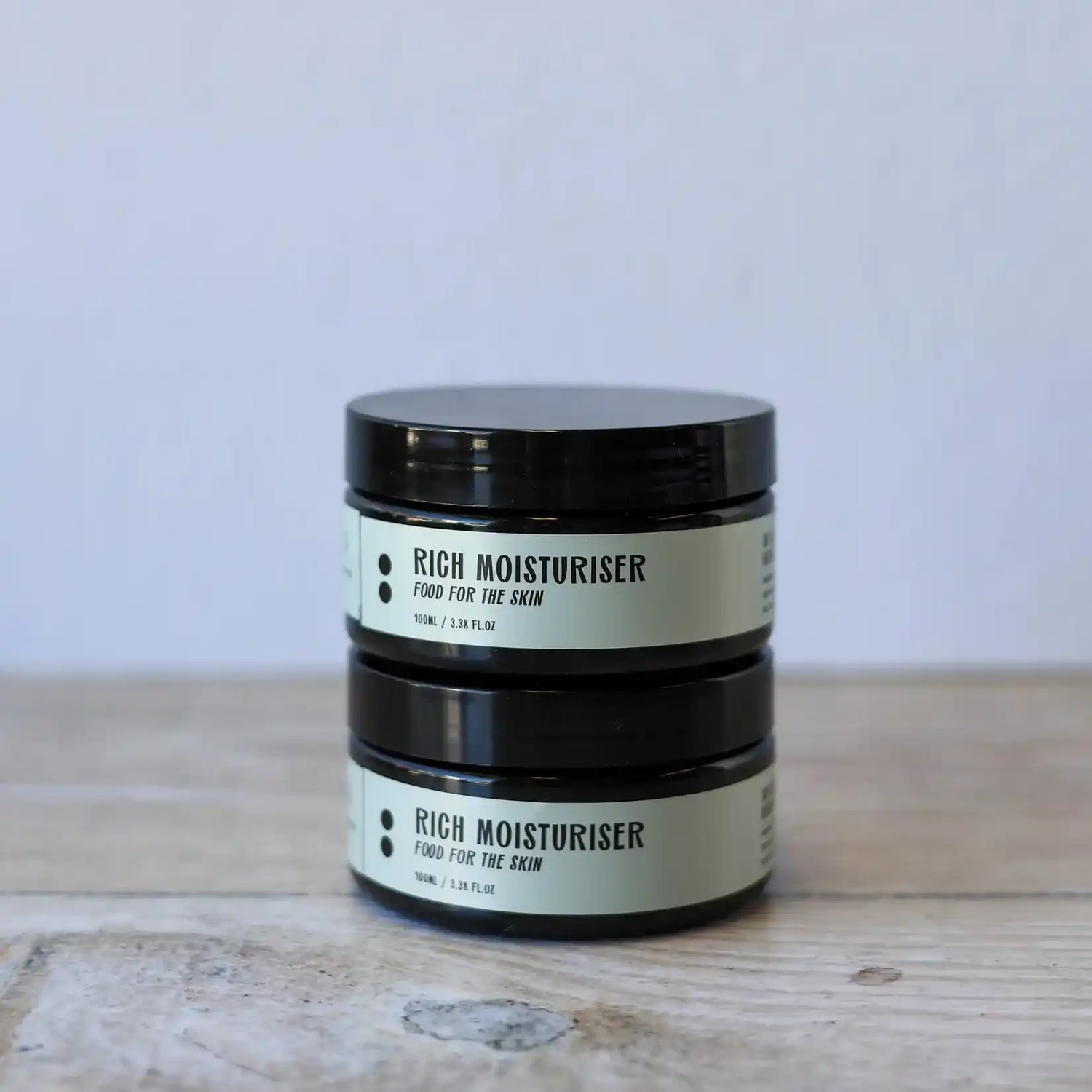 Two stacked jars of rich moisturizer.